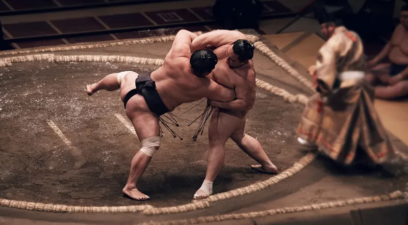 Overhead view of a live sumo match with a gyoji referee in ceremonial robes